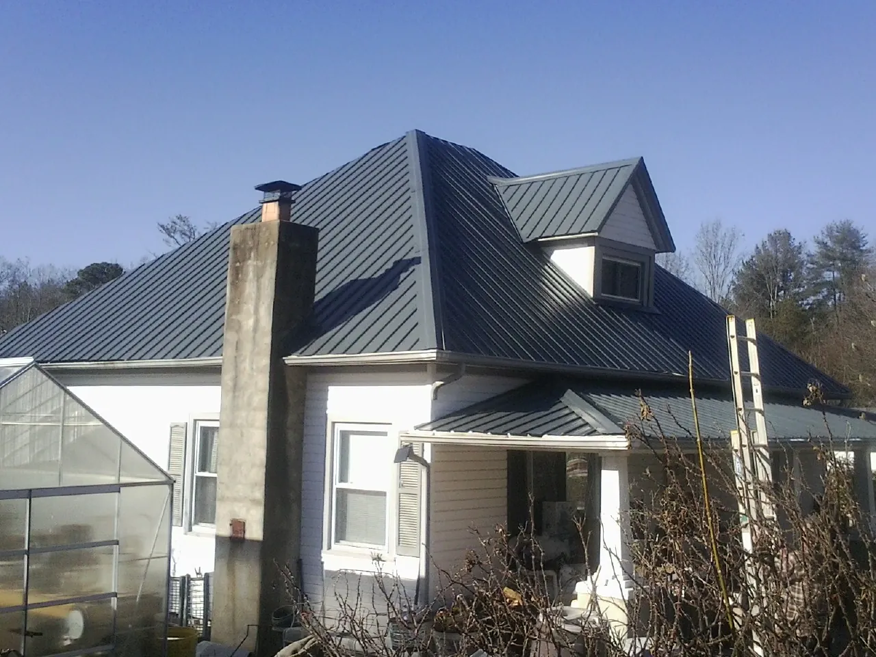 Dark blue standing seam metal roof on a white farmhouse with dormer — Slate & Tile Roof Repair by Roofing Brothers in Port Matilda