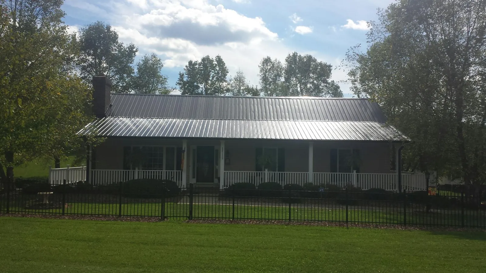 Gray metal roof on a brick ranch with a full width front porch — Gutter Guard Installation work by our crew in Port Matilda
