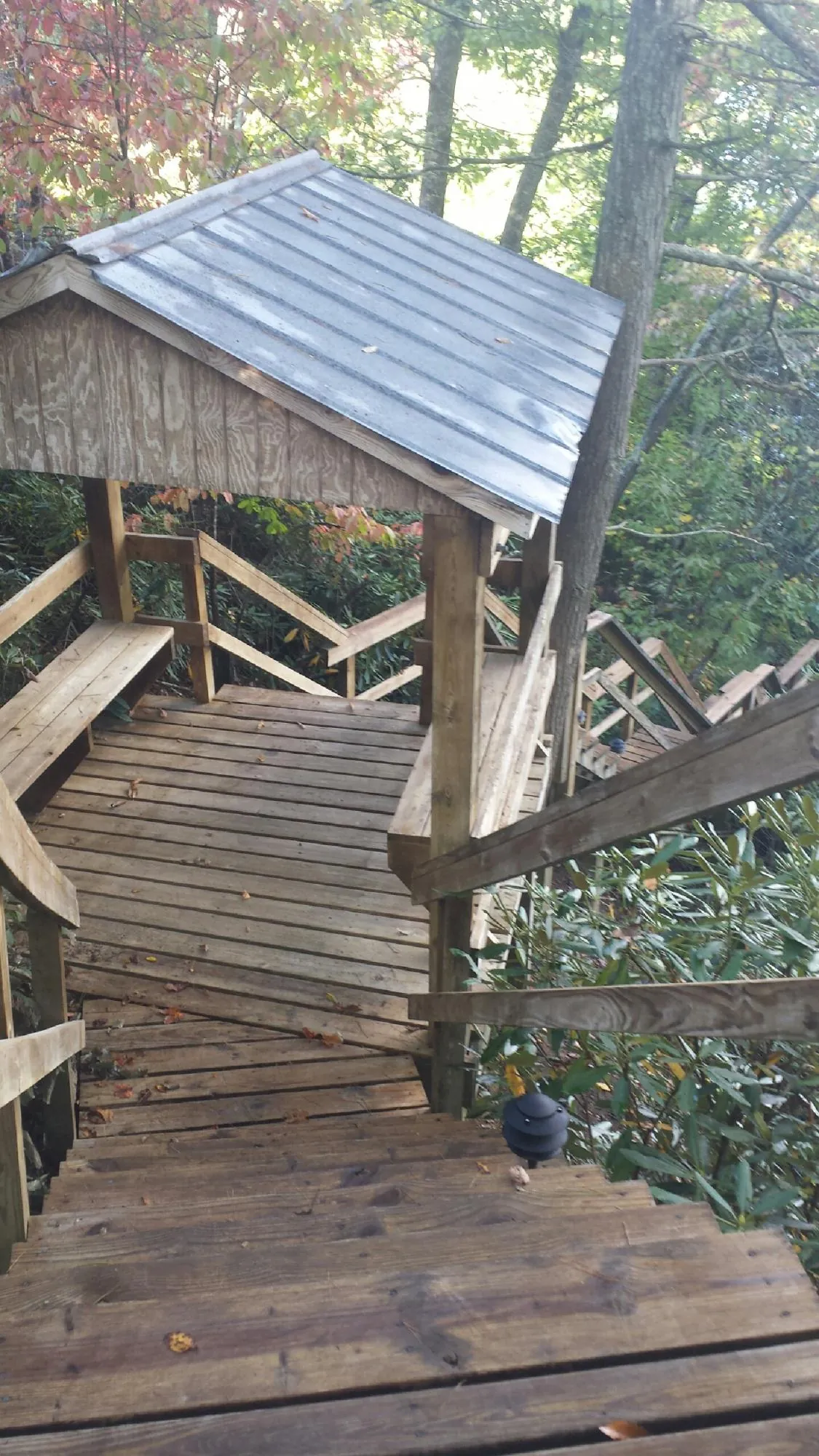 Metal roofed shelter over wooden steps on a wooded walkway — Skylight Repair & Installation work by our crew in Port Matilda