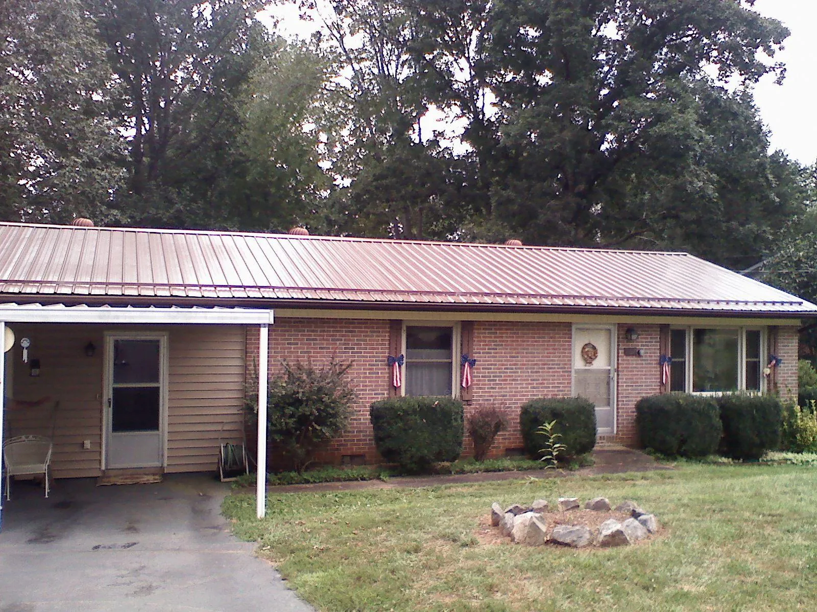 Bronze metal roof and carport on a brick ranch home — Roof Repair work by our crew in Port Matilda