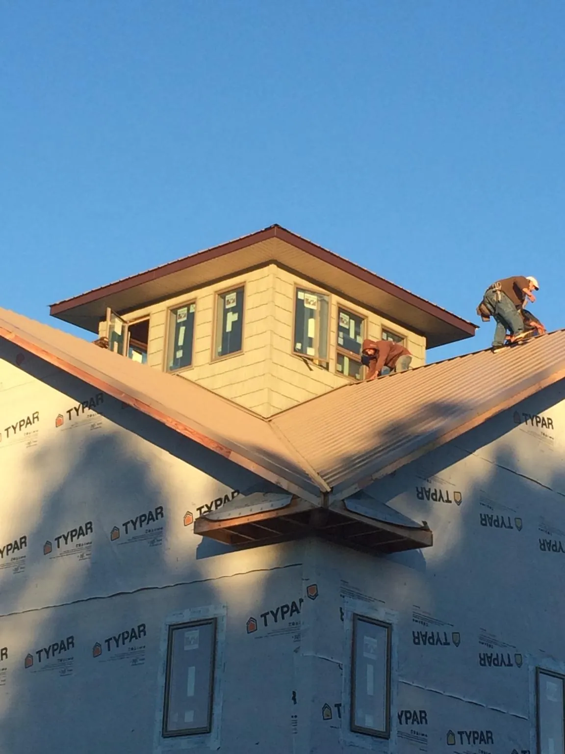 Roofers working around a rooftop cupola on a new metal roof at sunset — Roof Waterproofing in Port Matilda by Roofing Brothers